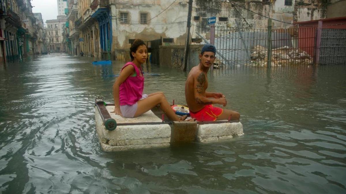 A couple floats down a flooded street in Havana atop a large piece of foam, after the passing of Hurricane Irma in Cuba on Sept. 10, 2017. Such flooding further damages poorly maintained homes and can lead to collapses.