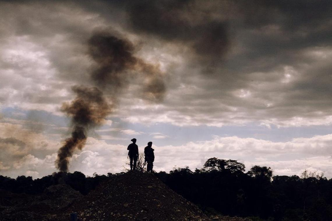 Police officers stand watch in southwestern Colombia after authorities destroyed backhoes involved in illegal gold mining operations.