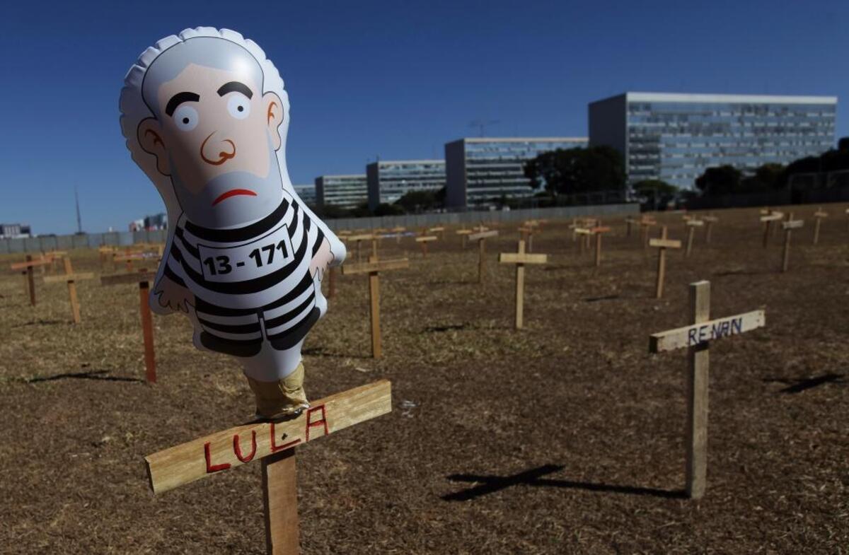 An inflatable doll representing former Brazilian President Luiz Inacio Lula da Silva wearing prison clothes stands on a cross with his name in Brasilia on Aug. 27, 2017. Demonstrators set crosses representing the death of corrupt politicians in protests across the country.