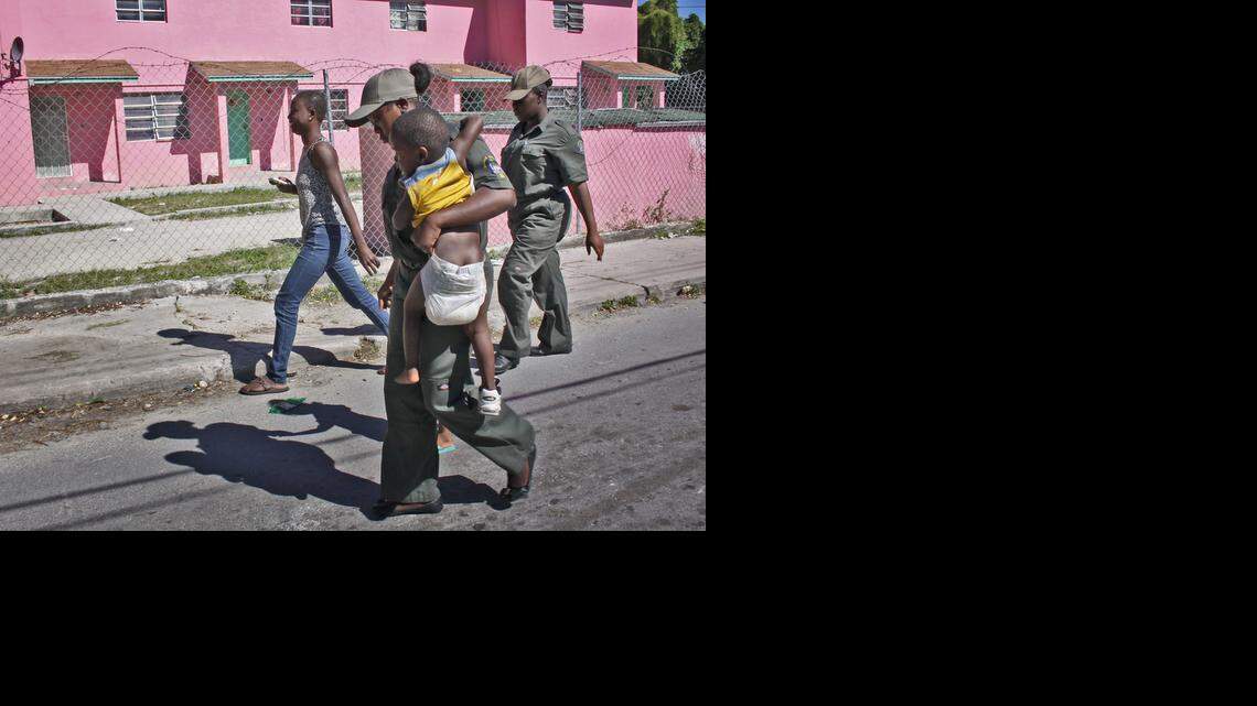 
Immigration officers escort a woman and child to the immigration bus bound for the Carmichael Road Detention Center on Saturday. Officials detained numerous suspected illegal immigrants during an island-wide immigration sweep.
