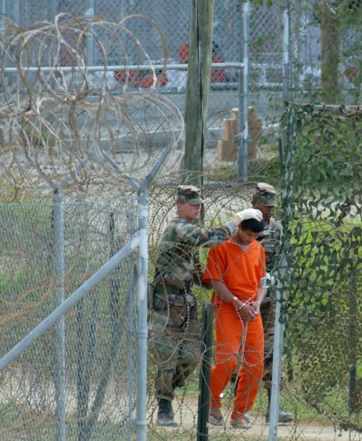 A detainee is escorted to interrogation by U.S. military guards at Camp X-Ray on Wednesday, Feb. 27, 2002.