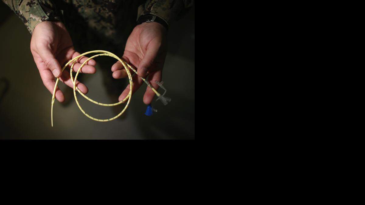 
A Navy doctor holds a feeding tube used to deliver a can of Ensure up the nose and down the back of the throat and into the stomach of a prison camp hunger striker on June 26, 2013 at the U.S. Navy base at Guantánamo Bay, Cuba. The military reviewed this photo as a condition of release.
