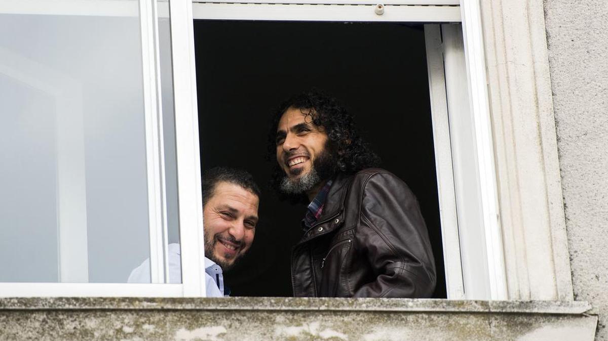 In this June 5, 2015 file photo, Abu Wa'el Dhiab, from Syria, right, and Adel bin Muhammad El Ouerghi, of Tunisia, both freed Guantánamo detainees, stand next to the window of their shared home in Montevideo, Uruguay.