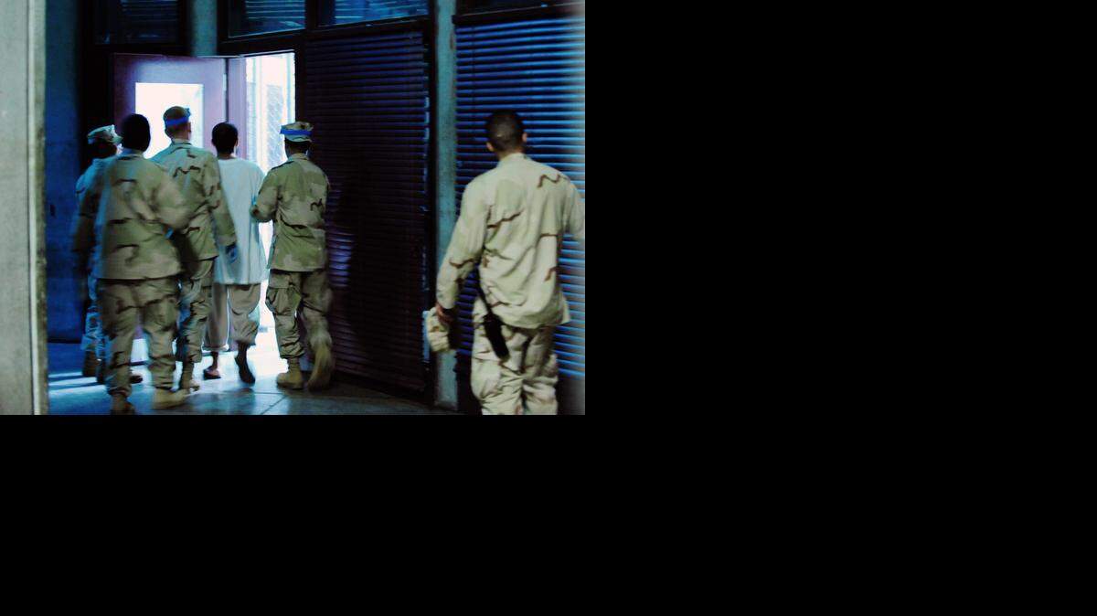 
Guantánamo guards escort a detainee inside Camp 6, a prison building that permits some communal confinement, on Oct. 9, 2011 in this U.S. military handout photo. 


