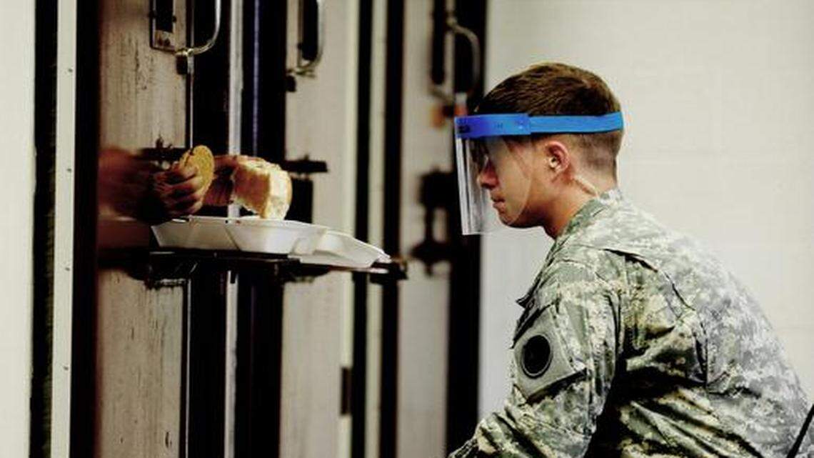 
An Army guard wear a splash mask feeds a war-on-terror detainee through a slot in a steel prison door at Guantanamo’s Camp 5 on Oct. 19, 2011 in this prison handout picture.
