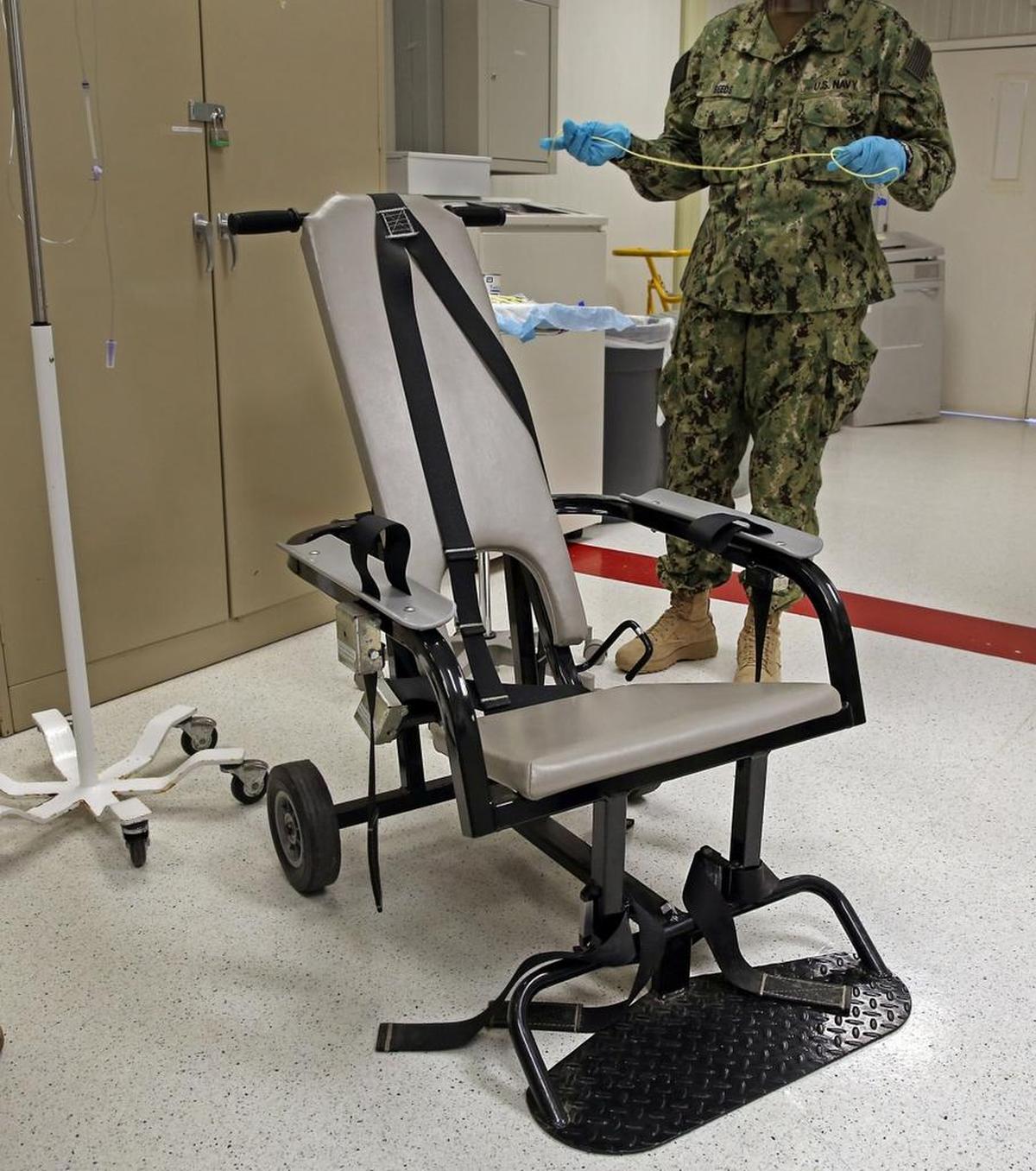 A Navy nurse stands by a restraint chair as she explains how she inserts a tube into a hunger striker’s stomach at the U.S. Navy base at Guantánamo Bay, Cuba, on Tuesday, Nov. 4, 2014 in this photo approved for release by the U.S. military.