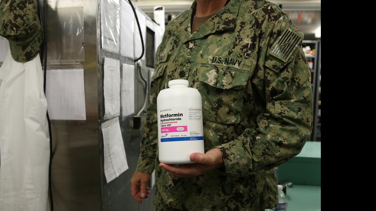 
A physician called the Senior Medical Officer holds up a drug used to treat diabetics at the U.S. Navy Base at Guantánamo Bay, Cuba, on Tuesday, July 7, 2015 in an annex of the Detention Center Hospital. The doctor's face cannot be shown as a condition of media access, and he reached for the medication to illustrate certain conditions among an aging detainee population of 116 captives that day. 
