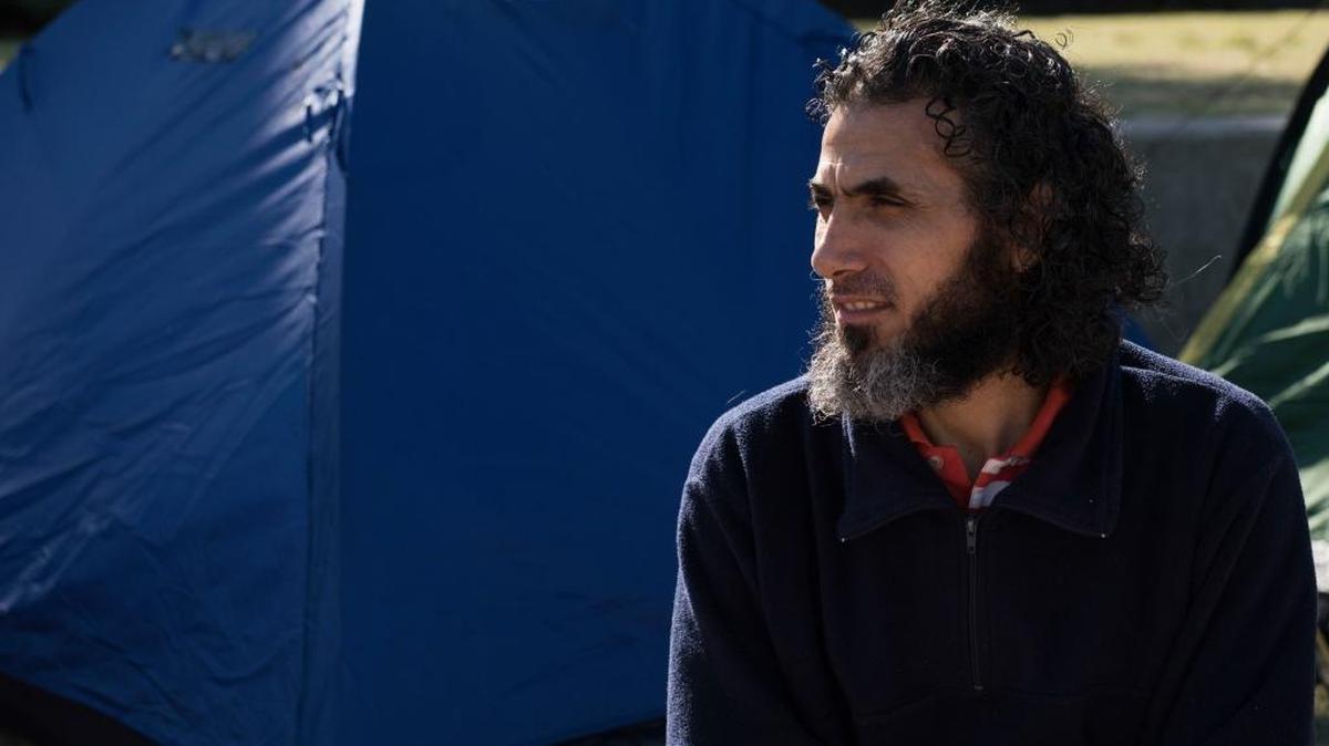 In this May 5, 2015 photo, former Guantánamo detainee and sometime hunger striker Abu Wa’el Dhiab, a Syrian, sits in front of the U.S. embassy while visiting former fellow detainees demanding financial assistance from the U.S., in Montevideo, Uruguay.