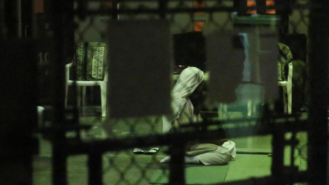 A detainee kneels in prayer at sunset on Saturday, Feb. 11, 2017 at Camp Six at Guantánamo’s Detention Center Zone. The military approved release of this photo.
