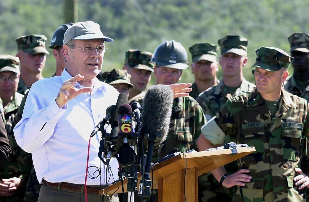 The troops and Marine Brig. Gen. Michael Lehnert, far right, listen as Secretary of Defense Donald H. Rumsfeld answers questions from the media during a brief press conference on Jan. 27, 2002 after touring Camp X-Ray.