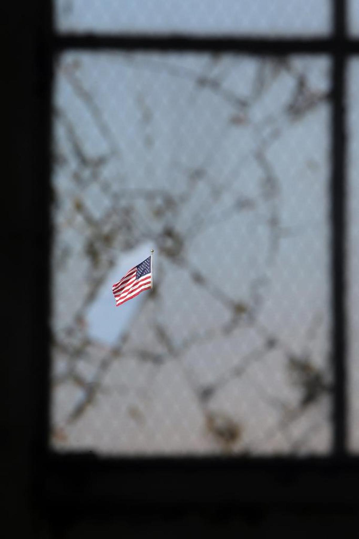 The American flag flying at the old courthouse as seen through a broken window at the old hanger, at the U.S. Navy base at Guantanamo Bay, Cuba, on Tuesday, Nov. 4, 2014 in this photo approved for release by the U.S. military.