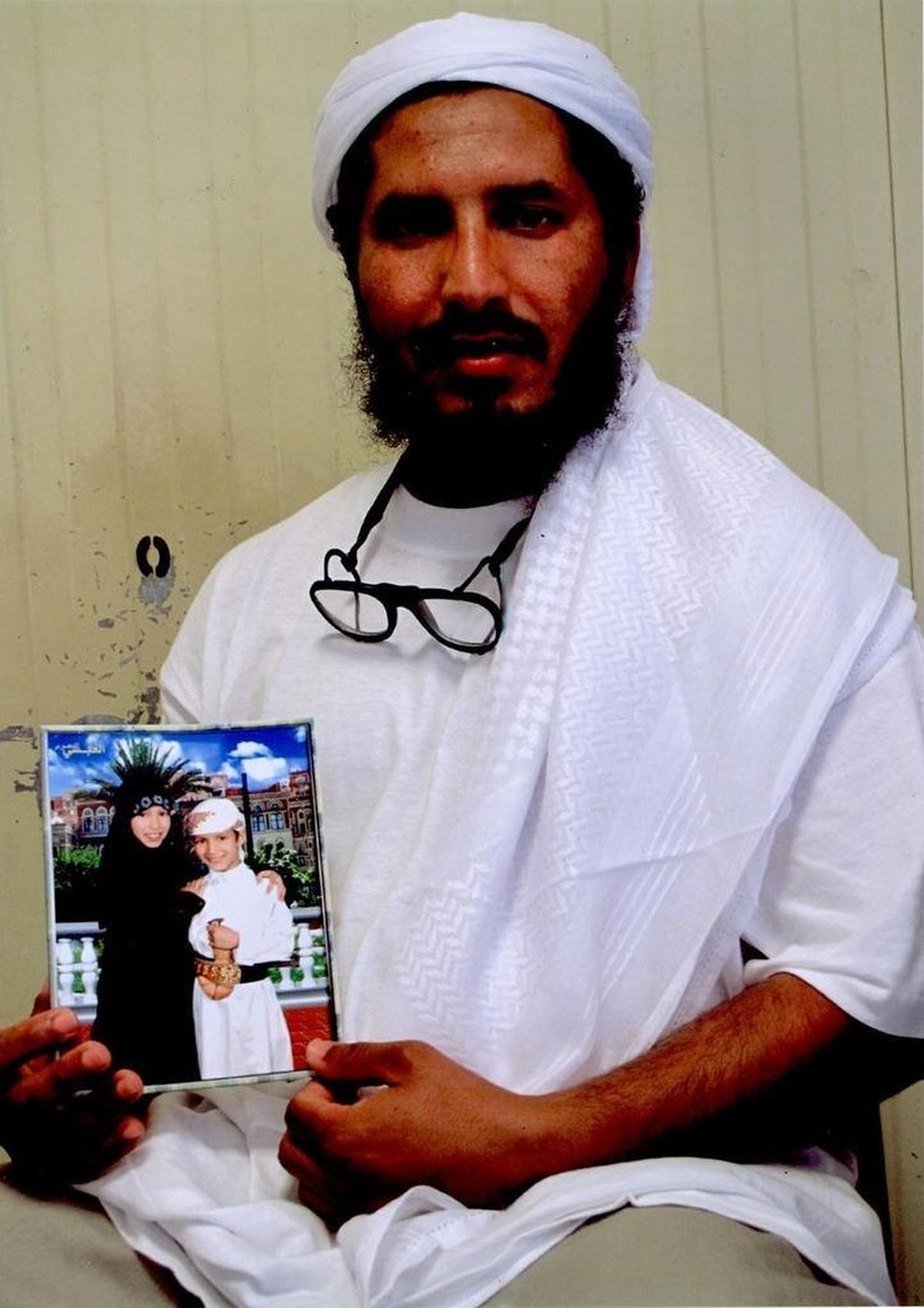 Ahmed al Darbi holds a photo of his children while he poses for the International Red Cross in this undated photo at Guantánamo provided to the Miami Herald by his attorneys