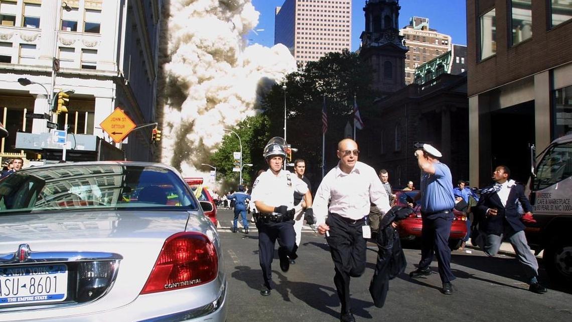 Police and pedestrians run for cover in New York City during the collapse of the first World Trade Center tower after the landmark skyscrapers were struck by two hijacked airplanes on Sept. 11, 2001