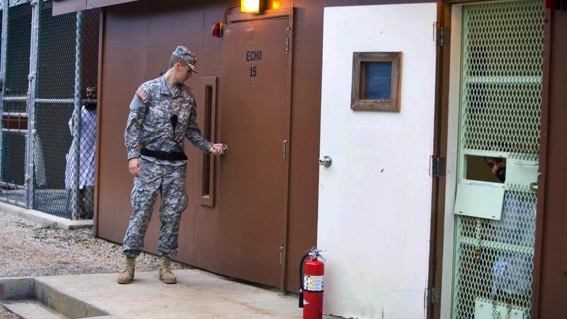 In this image reviewed by the U.S. military, Guantánamo detainees look out from fenced-in areas as a guard closes a door in Camp Echo, a detention facility where some lawyers hold meetings with captives, on the U.S. Navy Base in Guantánamo Bay, Cuba, on Nov. 19, 2008.