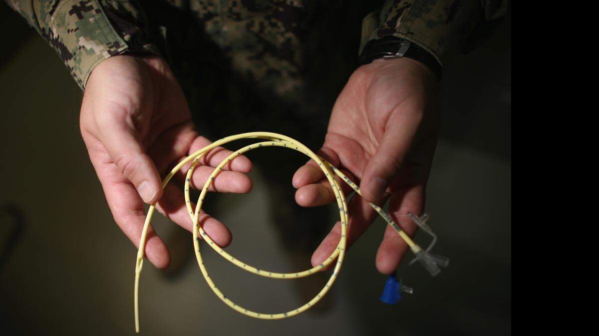 
A Navy doctor holds a feeding tube used to deliver a can of Ensure up the nose, down the back of the throat and into the stomach of a prison camp hunger striker on June 26, 2013 at the U.S. Navy base at Guantánamo Bay, Cuba. The military reviewed this photo as a condition of release.
