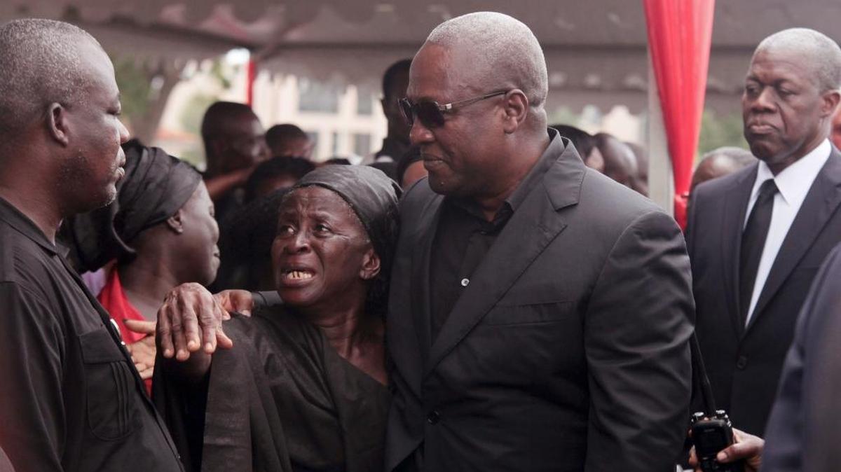 In this June 10, 2015 file photo Ghanaian president John Dramani Mahama, center, consoles a family member of a person that died at a national service for victim's of a gas station that ignited in Accra, Ghana.