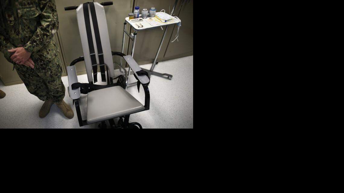 
In this photo Nov. 20, 2013 file photo reviewed by the U.S. military, a U.S. Navy nurse stands next to a chair with restraints, used for force-feeding, and a tray displaying nutritional shakes, a tube for feeding through the nose, and lubricants, including a jar of olive oil, during a tour of the detainee hospital at Guantanamo Bay Naval Base in Cuba. 
