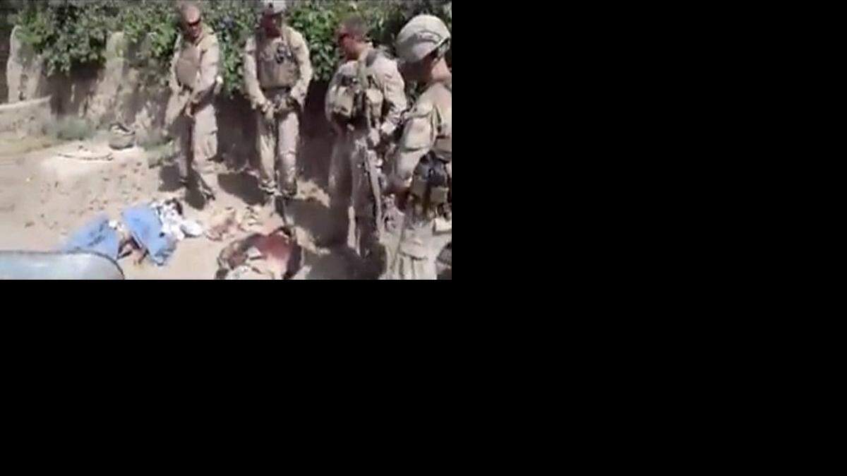 
This image made on Thursday, Jan. 12, 2012 from undated video posted on the Internet on Wednesday, Jan. 11, 2012 by a YouTube user who identified themself as “semperfiLoneVoice” shows men in U.S. Marine combat gear, standing in a semi-circle over three bodies. 
