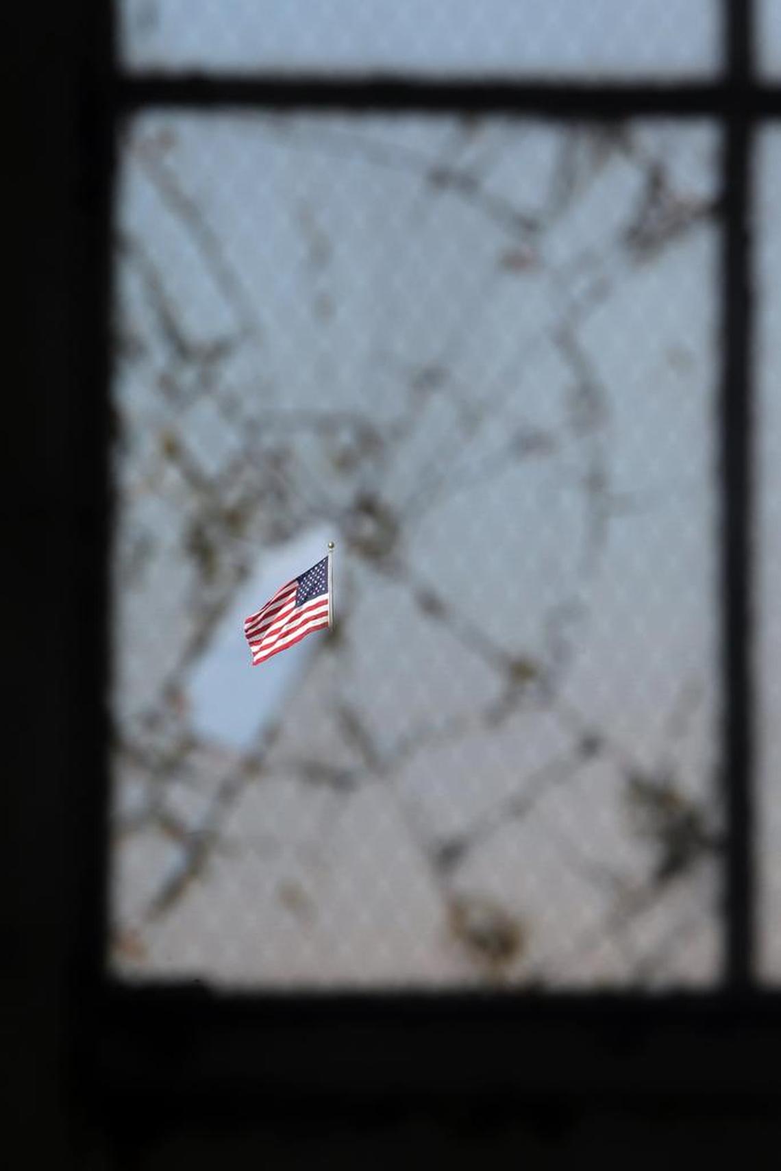The American flag flying over Camp Justice as seen through a broken window at an old hangar at the U.S. Navy base at Guantánamo Bay, Cuba, on Tuesday, Nov. 4, 2014 in this photo approved for release by the U.S. military.