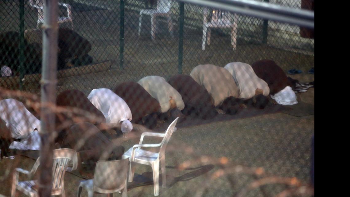 
War-on-terror captives from two different cellblocks, separated by a fence, break their daytime Ramadan fast as they assemble for communal evening prayers at the Camp 6 prison building for cooperative captives at the U.S. Navy base at Guantánamo Bay, Cuba, on Tuesday, July 7, 2015. This photo was taken through a closed window. U.S. Army soldiers reviewed this photo invoking Pentagon security restrictions and cleared it for release.
