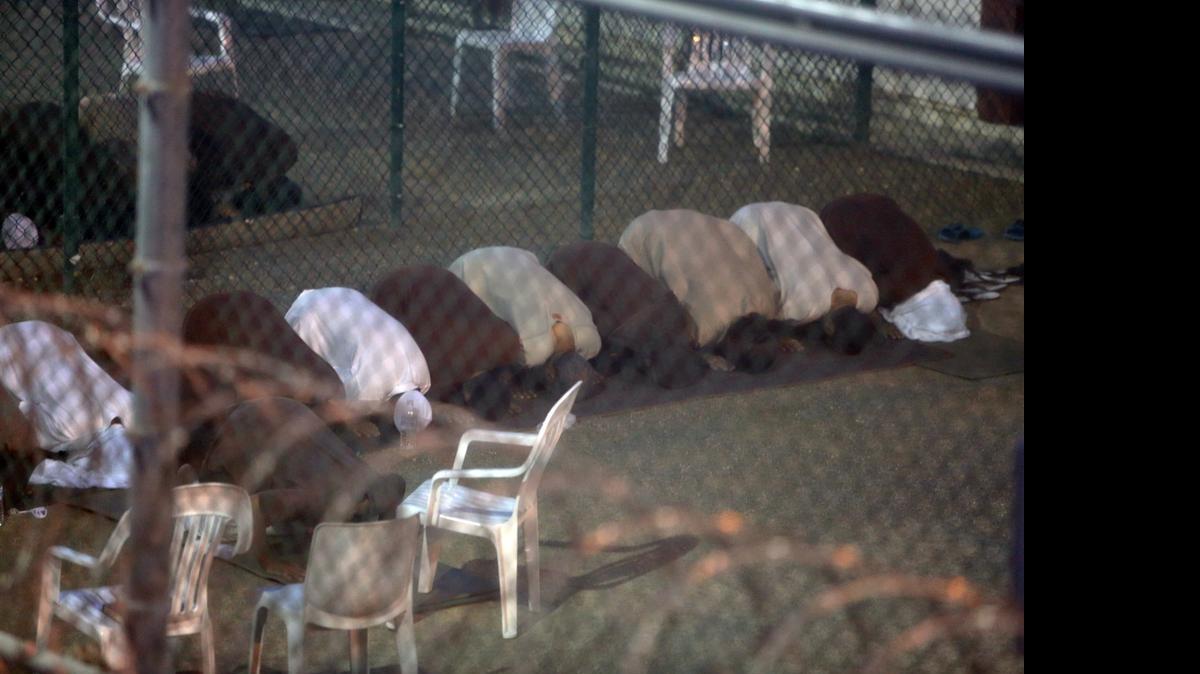 
War-on-terror captives from two different cellblocks, separated by a fence, break their daytime Ramadan fast as they assemble for communal evening prayers at the Camp 6 prison building for cooperative captives at the U.S. Navy base at Guantánamo Bay, Cuba, on Tuesday, July 7, 2015. This photo was taken through a closed window. U.S. Army soldiers reviewed this photo invoking Pentagon security restrictions and cleared it for release.
