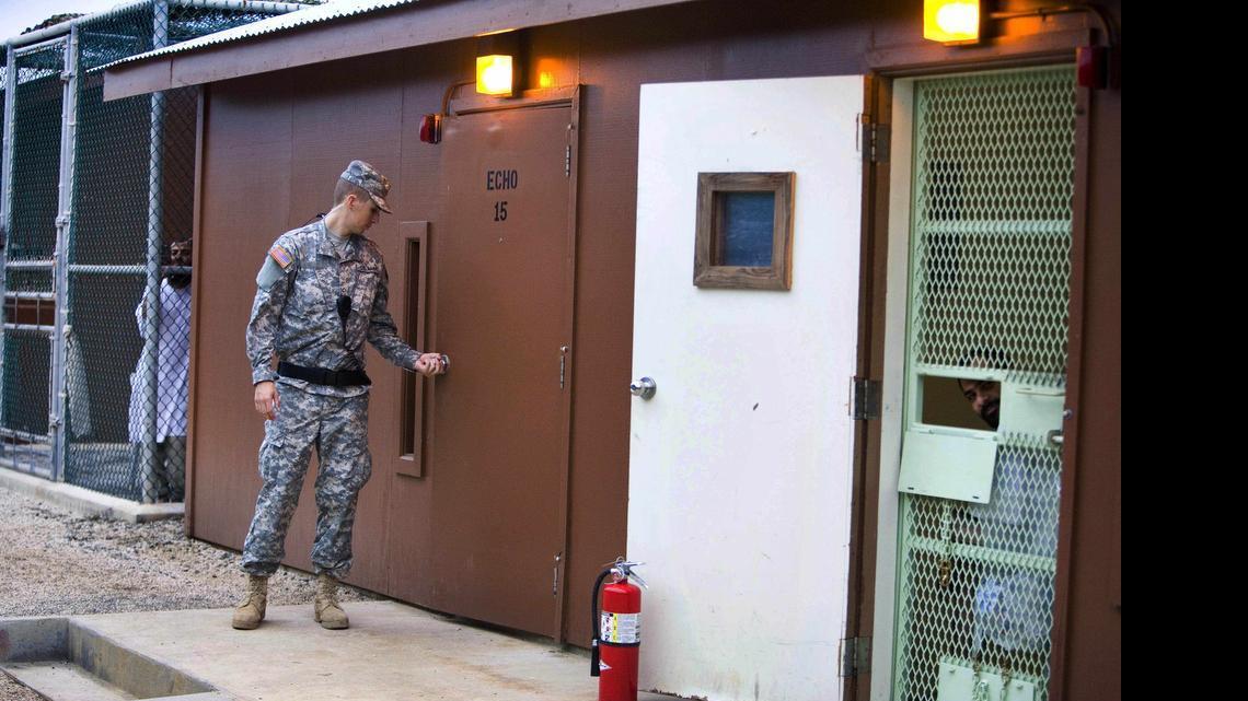 
In this image reviewed by the U.S. military, Guantánamo detainees look out from fenced-in areas as a guard closes a door in Camp Echo detention facility on the U.S. Navy Base in Guantánamo Bay, Cuba, Wednesday, Nov. 19, 2008. Lawyers have brought meals and treats to detainees at Camp Echo since 2005, a U.S. military accommodation ending this week.
