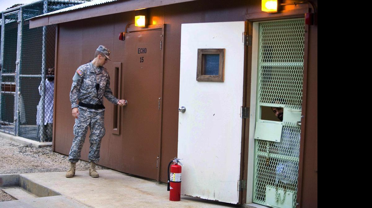
In this image reviewed by the U.S. military, Guantánamo detainees look out from fenced-in areas as a guard closes a door in Camp Echo detention facility on the U.S. Navy Base in Guantánamo Bay, Cuba, Wednesday, Nov. 19, 2008. Lawyers have brought meals and treats to detainees at Camp Echo since 2005, a U.S. military accommodation ending this week.
