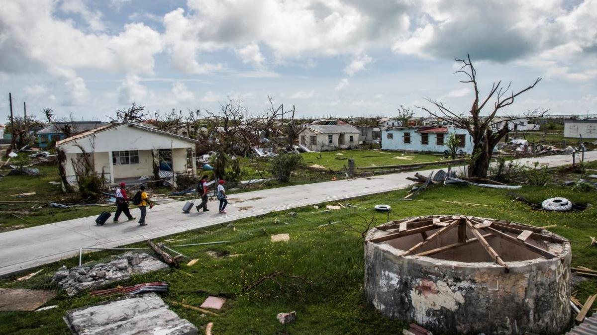 A Red Cross crew accompanies Peter Cuffy and his wife, Jenita Cuffy, as they walk through Codrington, their town on the island of Barbuda, in the aftermath of Hurricane Irma. Their home is among the many damaged by the storm.