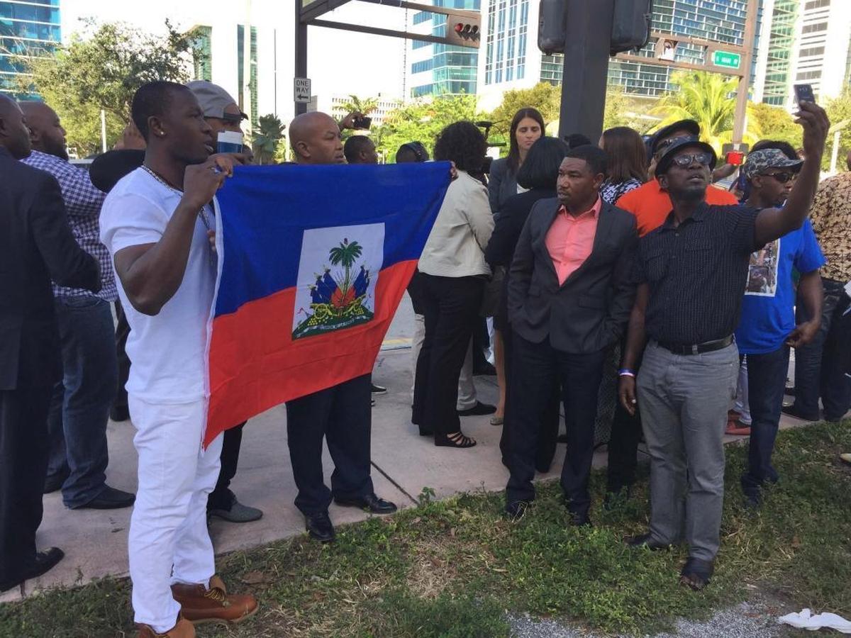 Supporters of Haitian-senator elect Guy Philippe, charged with drug trafficking by U.S. prosecutors, hold up Haiti's flag outside the federal courthouse in Miami on Friday, January 13, 2017.