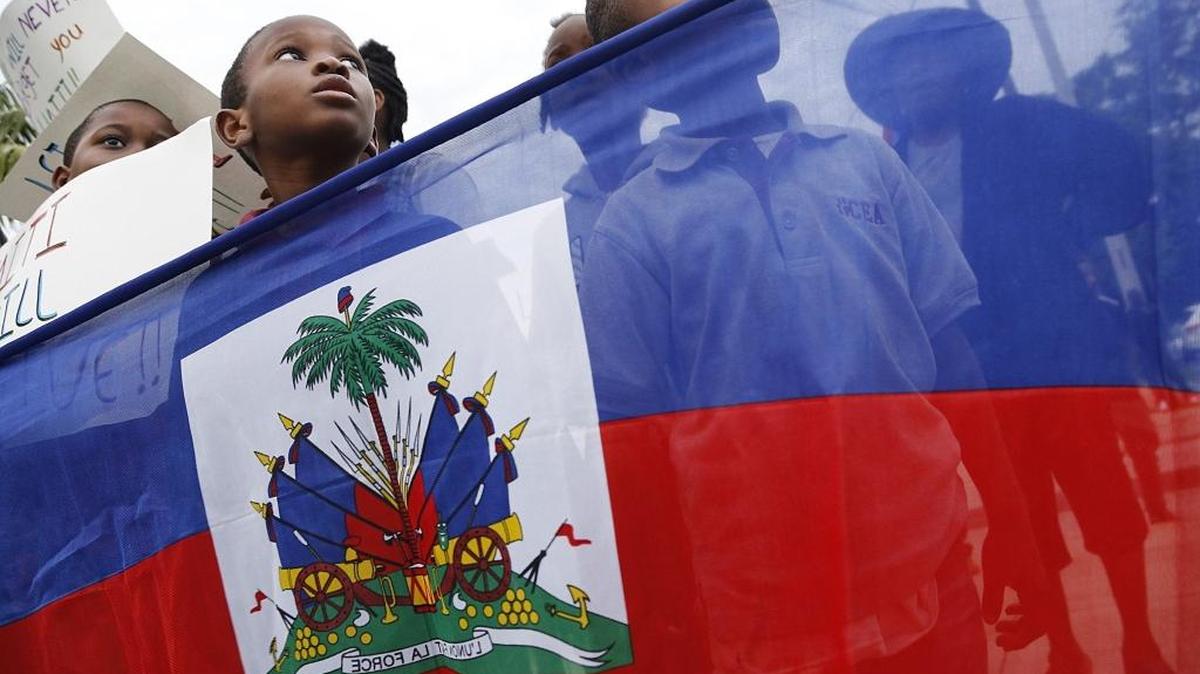 Guervens Jeune, left, Ralph Polynice, center, and Wedner Petit-Deu stand behind the Haitian flag as they enter the Little Haiti Cultural Complex. On Tuesday, Jan. 12, 2016, Miami’s Haitian community held a moment of silence at the Toussaint L’Ouverture statue then walked to the Little Haiti Cultural Complex for a prayer vigil in remembrance of those who died and were injured by the Haiti earthquake of 2010.