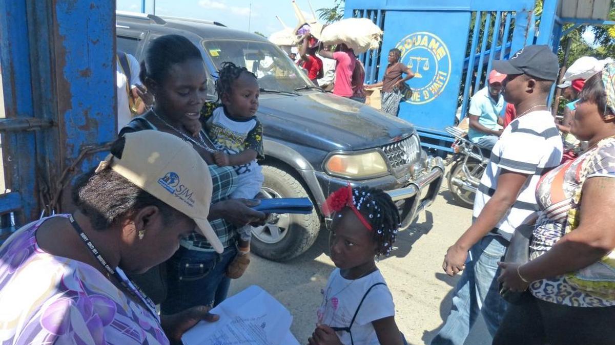 A lo largo de la frontera entre Haití y República Dominicana en Ouanaminthe, un trabajador de protección infantil de la agencia de bienestar infantil de Haití interroga a una madre haitiana que se dirige a través del río a Dajabón, en la República Dominicana.