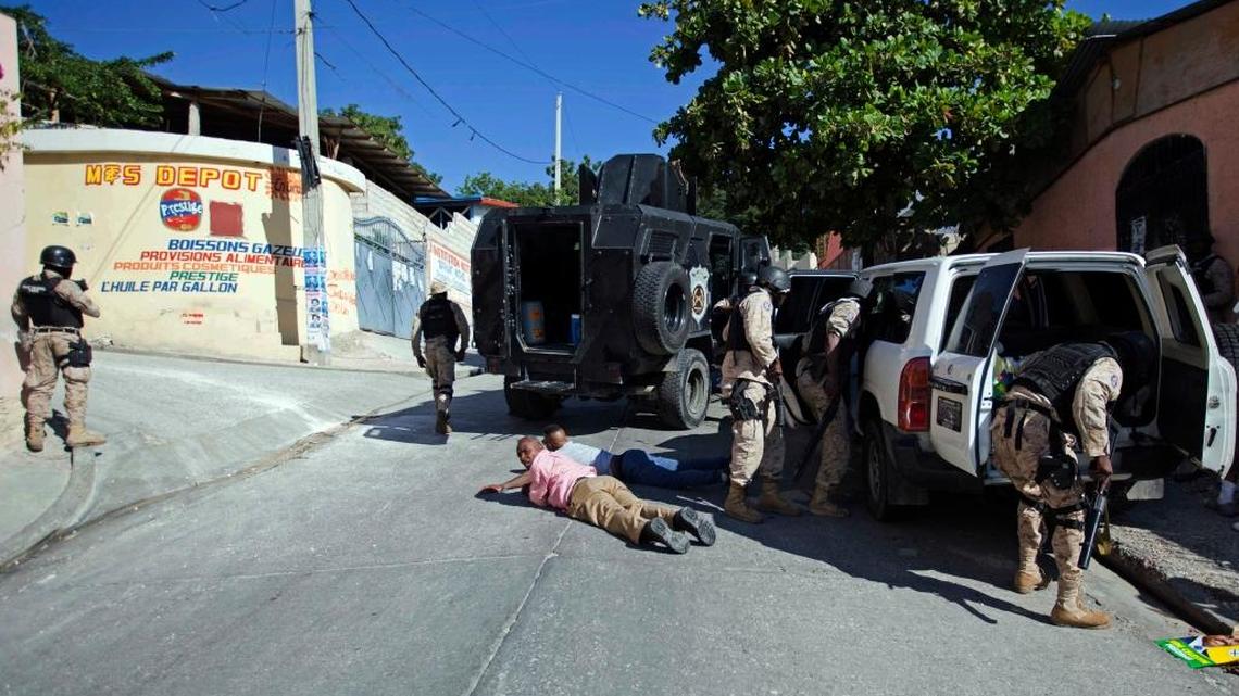 Supporters of presidential candidate Jude Celestin lay on the ground after police pulled them over to inspect their car, on the fringes of a protest against election results in Port-au-Prince, Haiti, Saturday, Nov. 7, 2015. Police let the men go afterward. Preliminary election results showed Celestin will face government-backed candidate Jovenel Moise in a runoff vote in December.