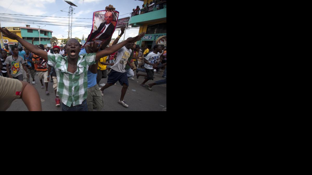
Demonstrators march during an anti-government protest, one holding a poster with the photo of Jean-Bertrand Aristide, in Port-au-Prince, Haiti, Sunday, Oct. 26, 2014. 
