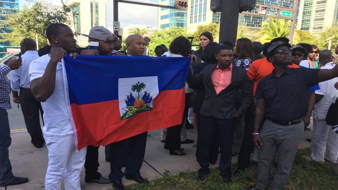 Supporters of Haitian Senator-elect Guy Philippe, charged with drug trafficking by U.S. prosecutors, hold up Haiti's flag outside the federal courthouse in Miami on Friday, January 13, 2017.