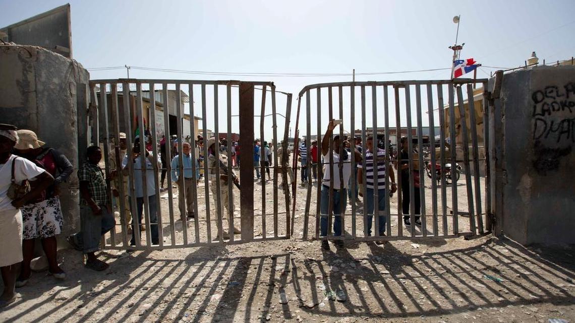 
In this Aug. 4, 2015 photo, Dominican Republic soldiers and civilians stand at the gate that separates the D.R. from in Malpasse Haiti. After the D.R.'s June 17 deadline to apply for legal residency under a new program to organize the flow of migrants across the border from Haiti, more than 288,000 people applied. So far about 25,000 have received their documents while another 40,000 have been approved. The Dominican government says 66,000 people have returned to Haiti since the deadline. 
