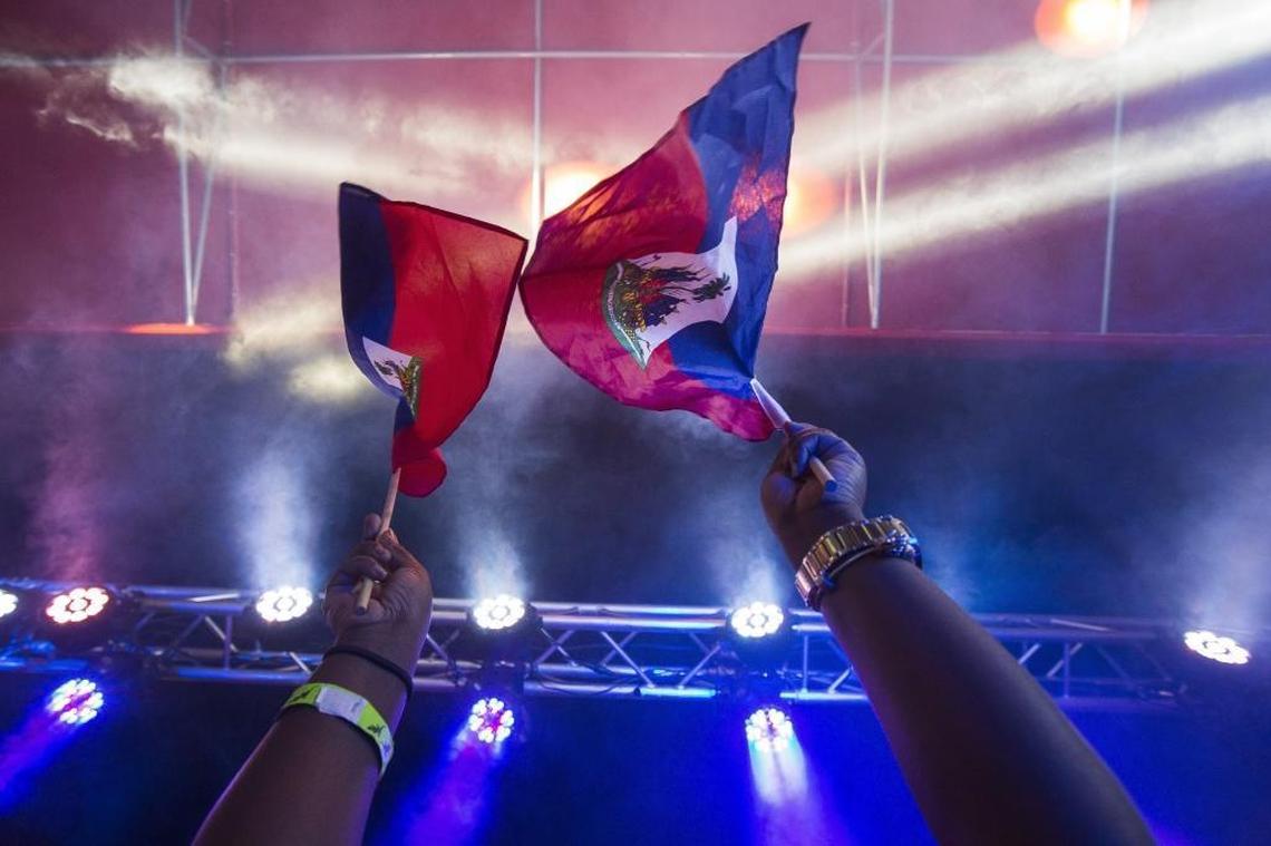 People cheer, dance and wave flags as they wait for Singer Wyclef Jean to perform during Sounds of Little Haiti at the Haitian Cultural Complex in Little Haiti on May 19, 2017.