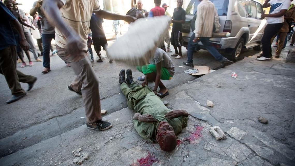 An anti-government protester drops a large cinder block on the head of Neroce R. Ciceron, a former captain in Haiti's disbanded army, as other protesters and members of the press stand behind while he’s beaten to death in Port-au-Prince, Haiti, on Friday. Members of Haiti's abolished military clashed with protesters who were demanding the resignation of Haiti's President Michel Martelly.