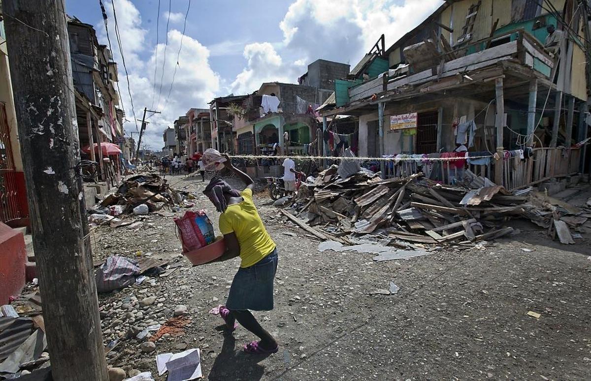 A woman ducks under a rope that was stretched across a street to keep traffic out in Jeremie, Haiti on Monday, October 10, 2016 after Hurricane Matthew uprooted trees, destroyed homes and farmlands in the western city.
