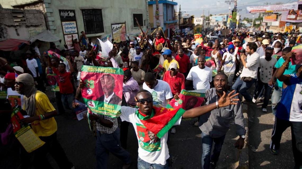 A protester holds a campaign poster of presidential candidate Moise Jean-Charles during a protest against the results of Oct. 25 elections, in Port-au-Prince, Haiti, Wednesday, Nov. 18, 2015. The demonstrators are organized by three political parties who have joined to demand the cancellation of the Oct. 25 presidential election, or removal of ruling party candidate Jovenel Moise who is set to face Jude Celestin in a Dec. 27 presidential runoff election.