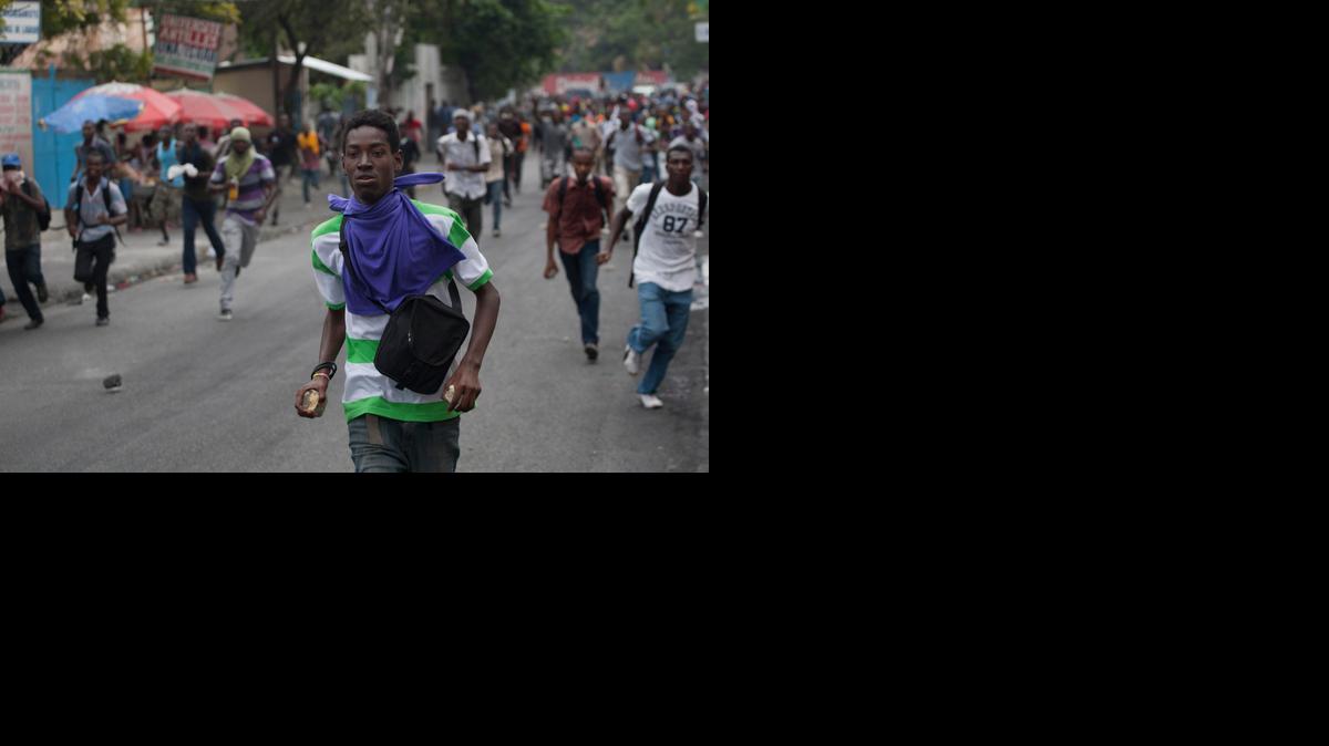 
Protesters run while holding stones during a protest demanding that the government lower fuel prices, in Port-au-Prince, Haiti, Friday, Feb. 13, 2015. Students marched through Haiti's capital to demand lower gas prices and the ouster of President Michel Martelly. 
