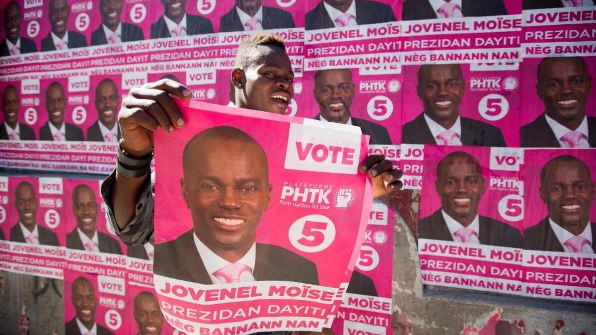 A supporter of presidential candidate Jovenel Moise holds up a campaign poster as he celebrates his candidate's victory in Petion-Ville, Haiti, Tuesday, Jan. 3, 2017. An electoral tribunal certified the presidential election victory of the first-time candidate. He will be sworn in on Feb. 7.