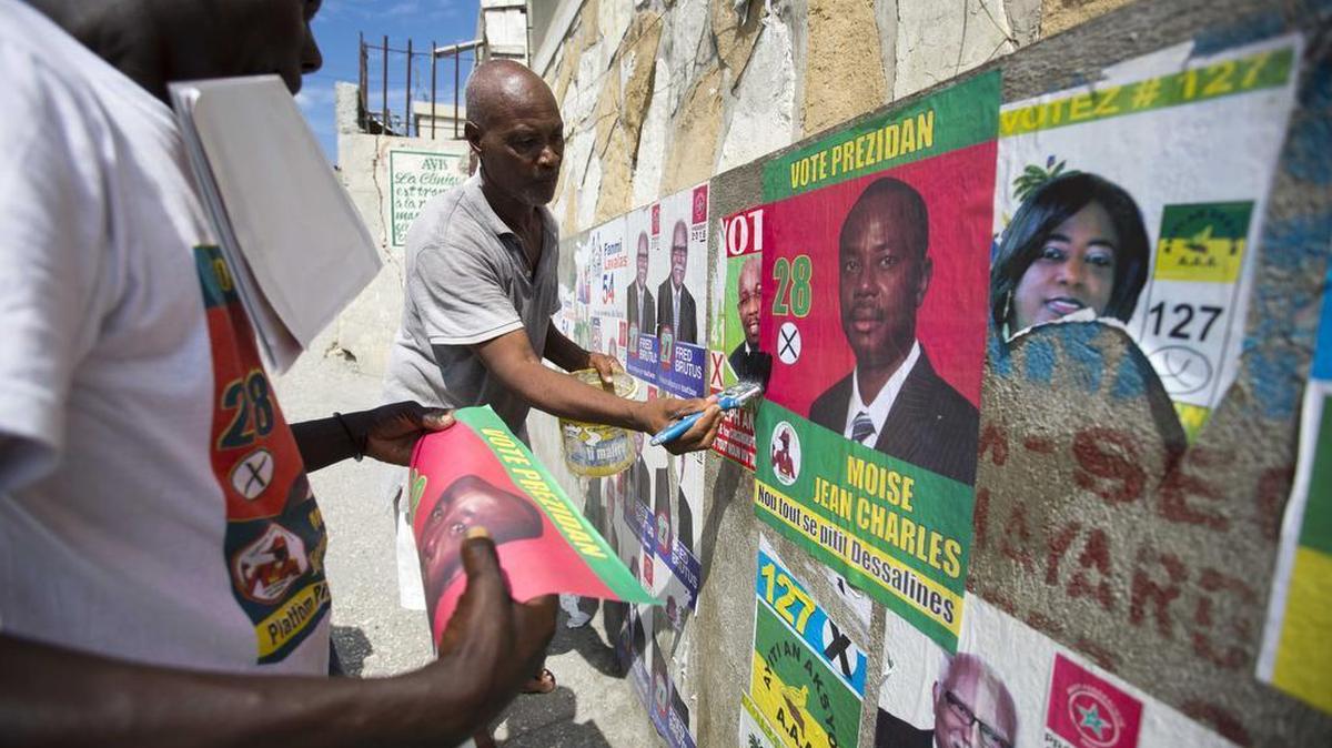 Supporters post election propaganda of presidential candidate Moise Jean Charles, of the Platform Pitit Dessalines political party, on a wall in Port-au-Prince, Haiti, Thursday, Oct. 22, 2015. This year’s unprecedented three rounds of balloting will pick Haiti’s next president, two-thirds of the Senate, the entire Chamber of Deputies and local offices. The Oct. 25 vote is expected to clear the sprawling presidential field for a runoff on Dec. 27 between the top two finishers.