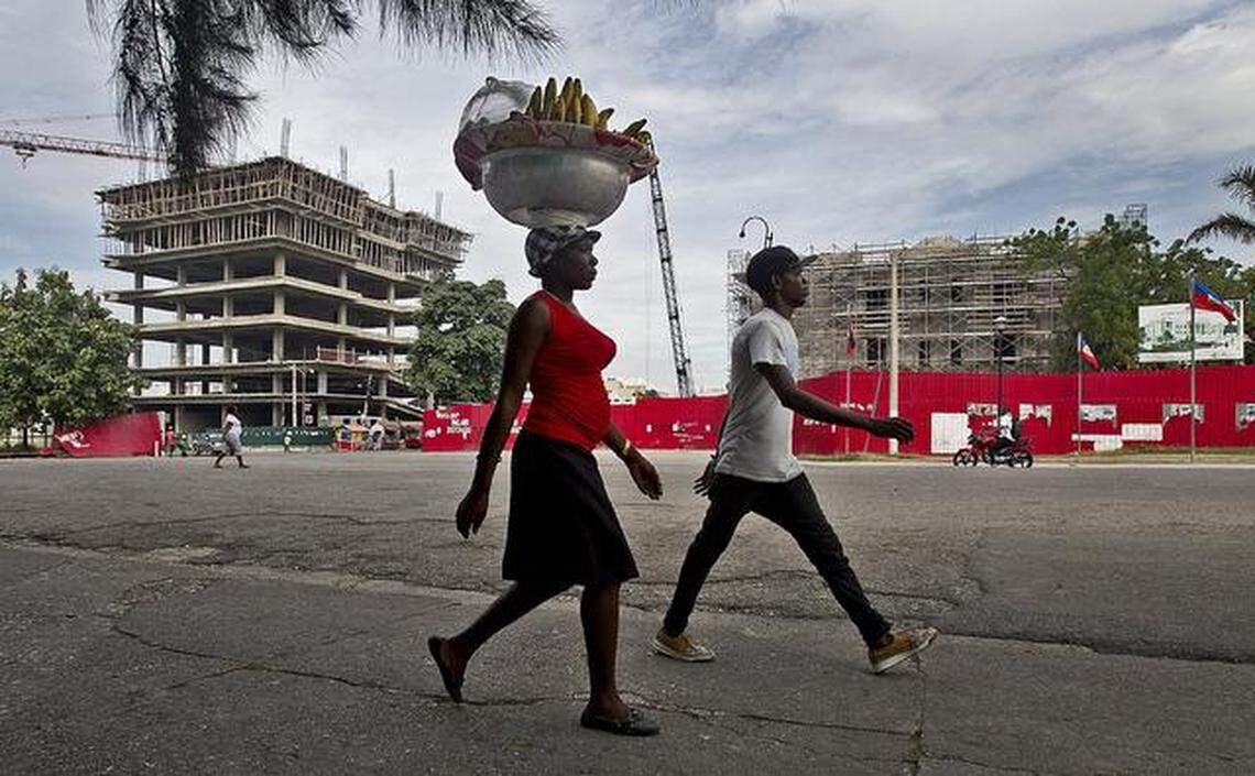 In this file photo from 2015, a woman walks along the Champ de Mars public square in Port-au-Prince where a new Ministry of Interior building, left, and Supreme Court, right, financed by Taiwan, were under construction five years after the Jan. 12, 2010, earthquake wiped out all of the government's ministries.