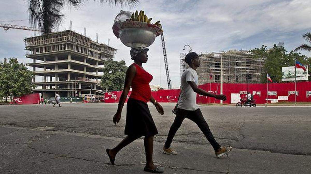In this file photo from 2015, a woman walks along the Champ de Mars public square in Port-au-Prince where a new Ministry of Interior building, left, and Supreme Court, right, financed by Taiwan, were under construction five years after the Jan. 12, 2010, earthquake wiped out all of the government's ministries.
