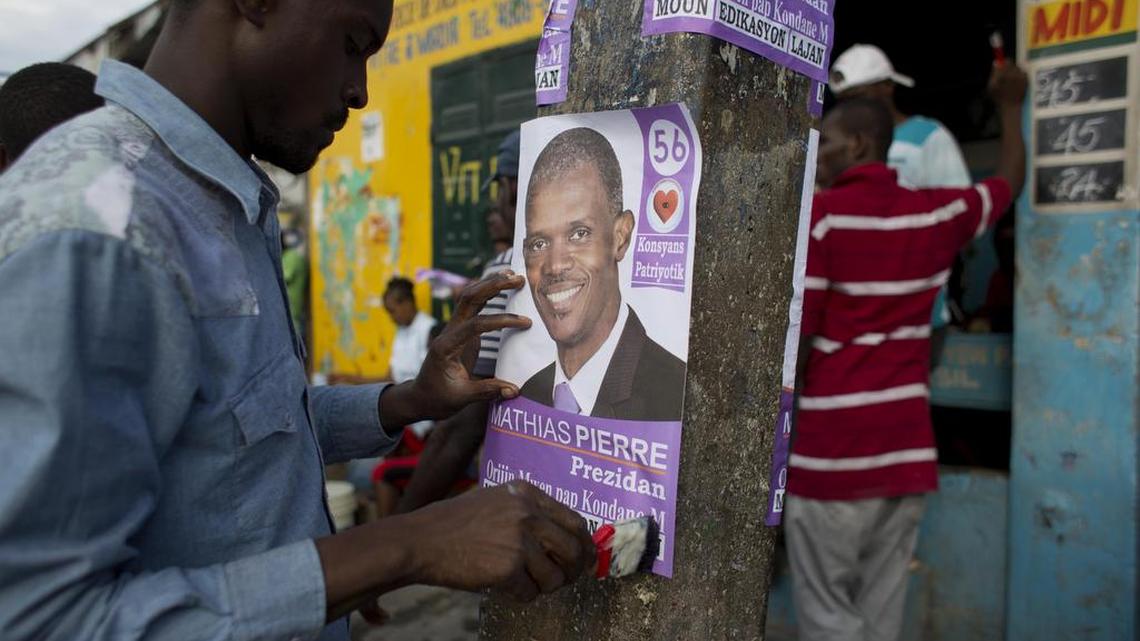 
In this Oct. 3, 2015 photo, a man pastes to a pole a campaign poster of presidential candidate Mathias Pierre, in Port-au-Prince, Haiti. Cities and towns across Haiti are plastered with colorful campaign ads, leaving voters struggling to differentiate a swarm of candidates who grin from posters, banners and billboards slapped on nearly everything that doesn't move and a few that do. In the first round of Haiti's presidential vote on Oct. 25, voters will choose from a field of 54 candidates.
