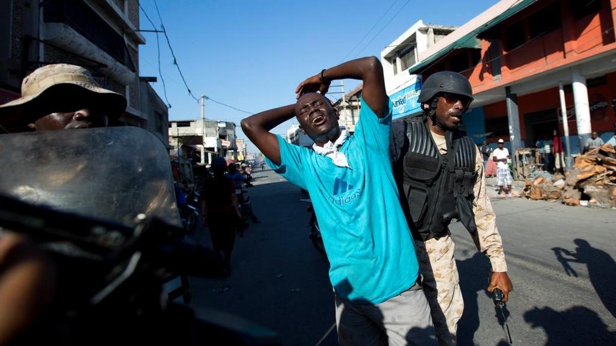 A man is detained by the national police during a protest against President Michel Martelly's government to demand the cancellation of the Jan. 24, elections, in Port-au-Prince, Haiti, Tuesday, Jan. 19, 2016. Disputed election results have brought paralyzing street protests and many broad accusations of electoral fraud from civil society and opposition groups.
