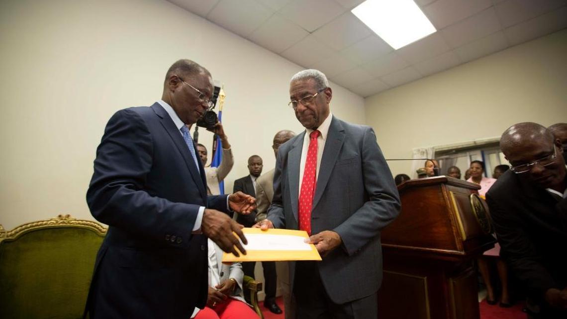 Interim President Jocelerme Privert, left, receives the election report from the president of the verification commission Francois Benoit, at the national palace in Port-au-Prince, Haiti, Monday, May 30, 2016. The commission recommended throwing out the disputed results of last year’s first-round presidential election because it appeared to be tainted by fraud.