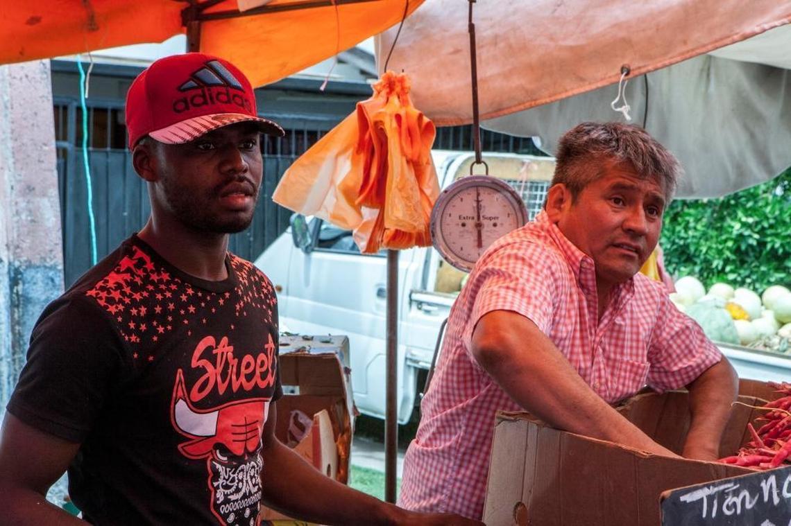Two days after arriving in Chile from Haiti, Sonel Vilcenat (left), 25, found a job when Rodrigo Castro, 47, saw him walking through a farmer's market in Cerrillos and asked if he wanted work. In Haiti, Vilcenat drove a motorcycle taxi. His goal is to make money and return to Haiti, he says.