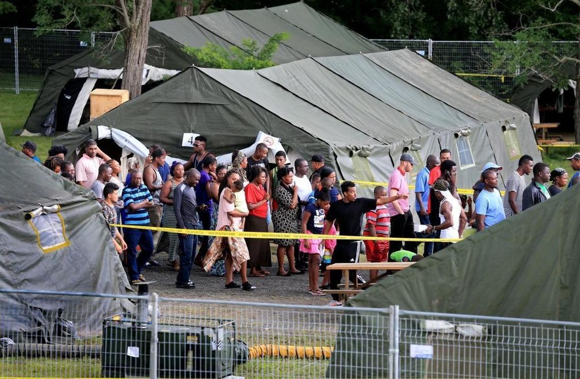 Migrants, sheltered in tents wait for food distribution near the Canada-US border in St. Bernard de Lacolle on Saturday, August 12, 2017. Thousands of people have crossed over in to Canada from an irregular crossing near the Champlain-Saint-Bernard-de-Lacolle border in hopes of finding residency in Canada. Among them are Haitians who worry that Temporary Protected Status in the US could soon end under the Trump administration.