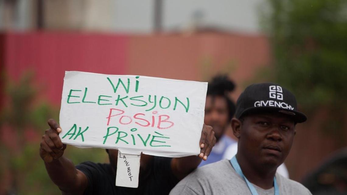 A supporter of presidential candidate Maryse Narcisse holds up a sign that reads in Creole "Yes the election is possible with Privert" referring to the interim President Jocelerme Privert, in Port-au-Prince, Haiti, Tuesday, June 21, 2016.